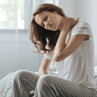 A woman rubs her neck, showcasing pain and irritation in need of remedying.