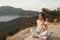 A woman sits on a rock enjoying meditative yoga.