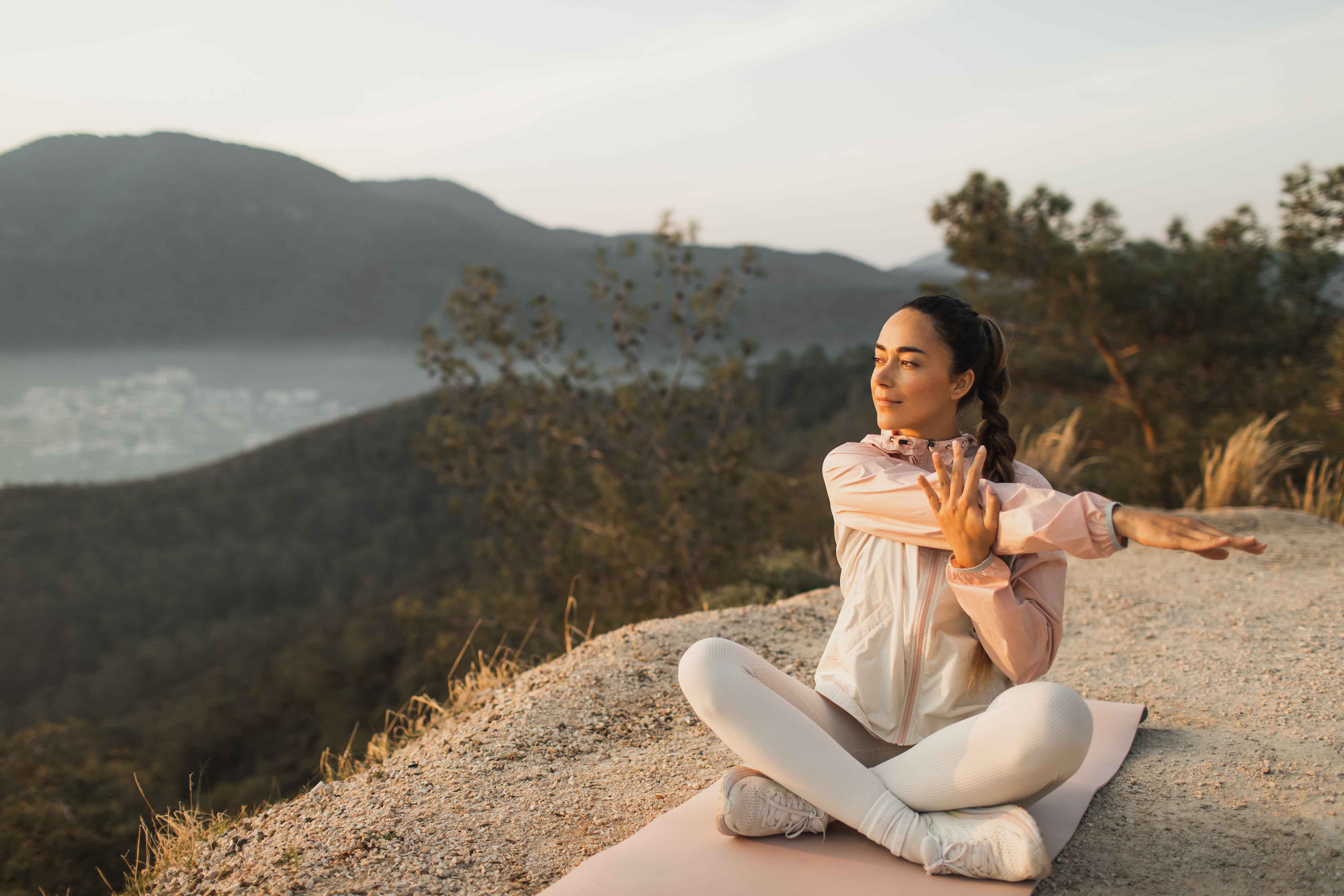 A woman sits on a rock enjoying meditative yoga.