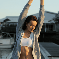 A woman stretches her arms over her head, indicating good energy and motivation.