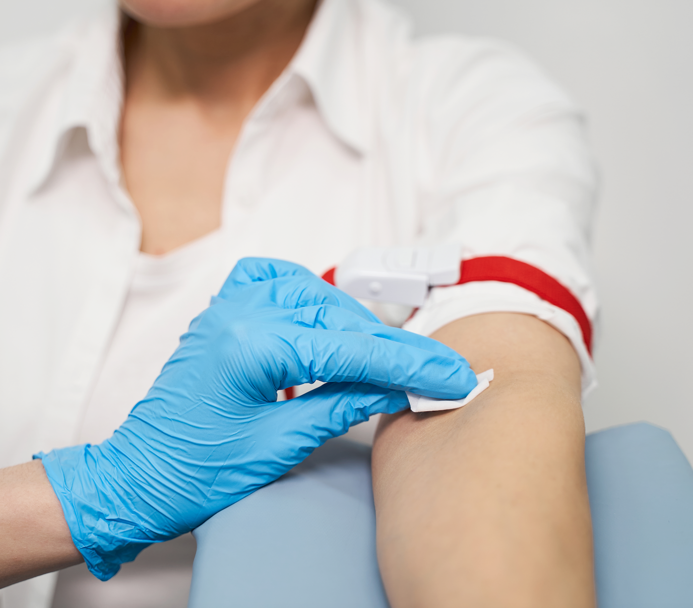 Preparing for a blood draw with blue gloves on.