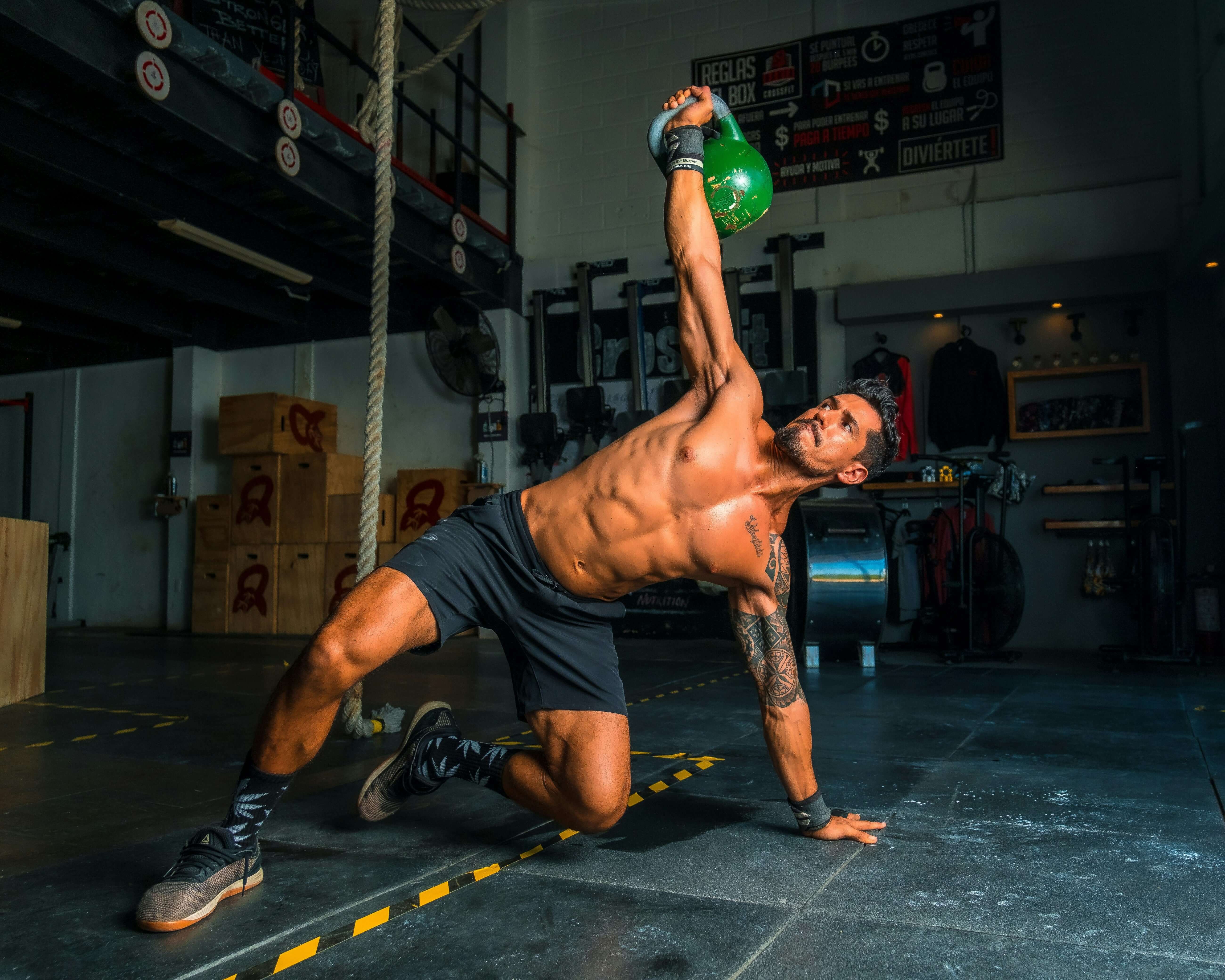 Man working out with kettle bells doing a shoulder and abs exercise.