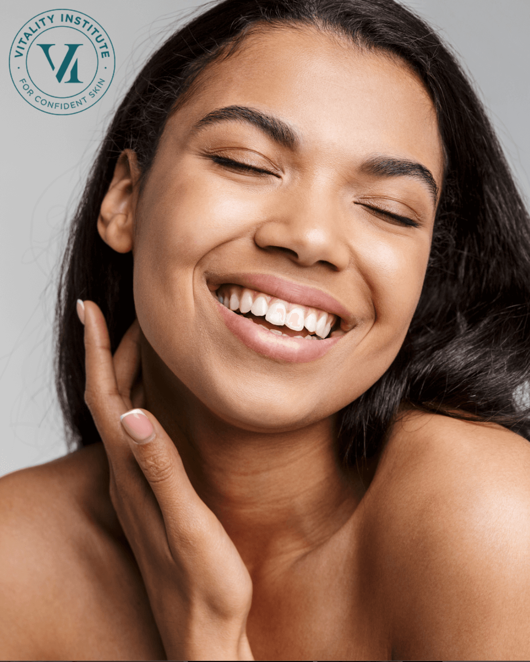 A woman touches her face and smiles to showcase healthy, vibrant skin, with a VI peel stamp in the corner of the image.