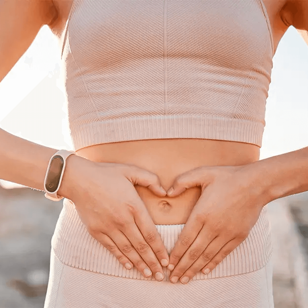 A woman presses gently on her gut to indicate desire for weight loss and improved gut health.